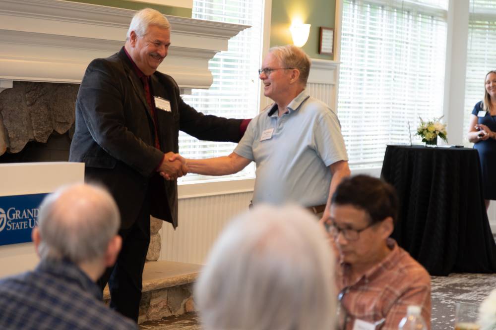 Dean Plotkowski shaking hands with another retiree